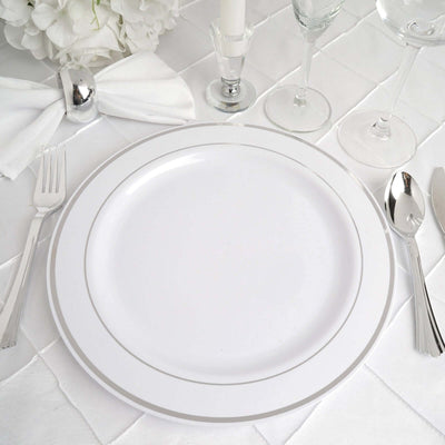 Elegant white dinner plate with silver trim on a table setting.