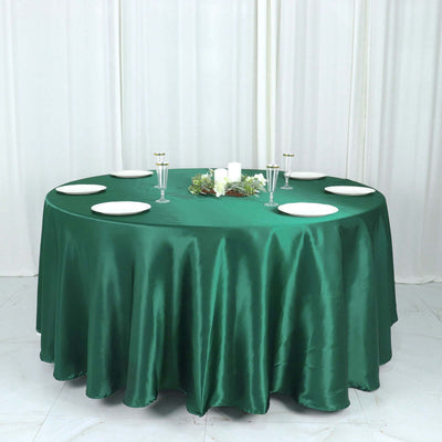 Round green tablecloth on a table set with plates and candles.