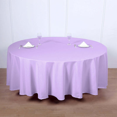 Round lavender tablecloth with elegant setting and utensils on a wooden surface.