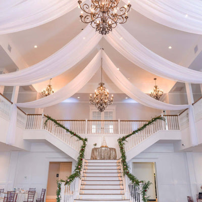 Elegant wedding venue with grand staircase and draped fabric decor.