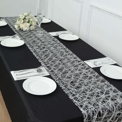 Elegant black table with a lace runner, plates, and floral centerpiece.