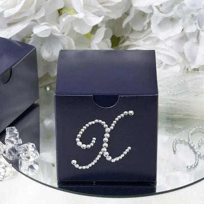 Navy gift box decorated with rhinestones and letter K on reflective surface.