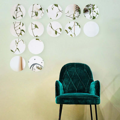 Green velvet chair with round mirrors and plant decor on a light wall.