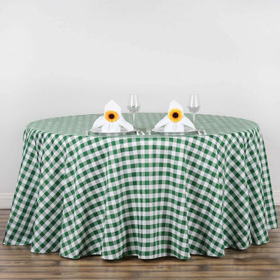 Green and white checkered tablecloth on a round table with napkins and glasses.