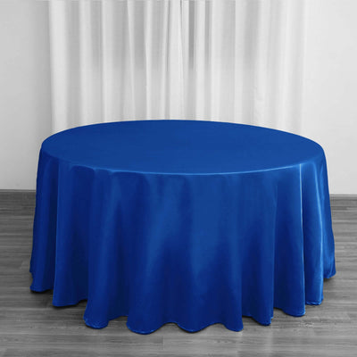 Round blue tablecloth on a wooden floor with sheer curtains in the background.
