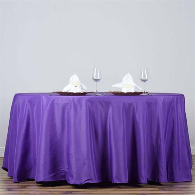 Purple tablecloth draped over a table with decorative napkins and glasses.