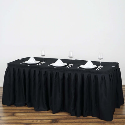 Black tablecloth draped over a table set with glassware and napkins.