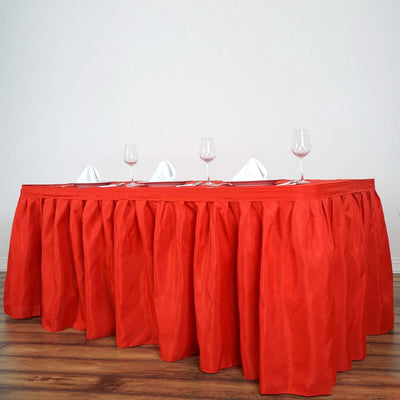 Red tablecloth with elegant draping, set for dining with wine glasses.
