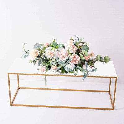 Floral arrangement on a gold table with greenery and pink roses