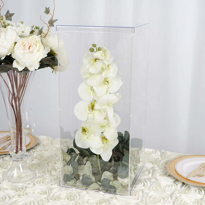 Artificial white orchid arrangement in a clear display case.