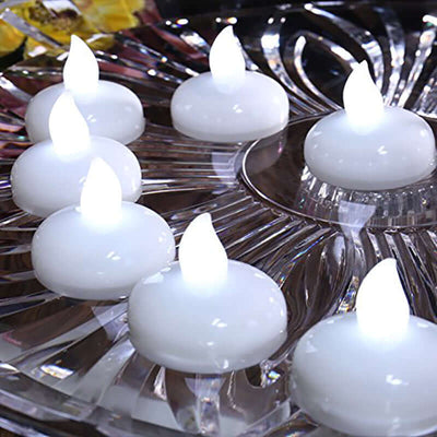 Set of eight white floating candles in a decorative glass dish.