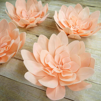 Peach paper flowers arranged on a wooden surface.