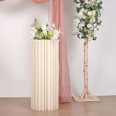 Cream-colored ribbed vase with flowers on a wooden floor.