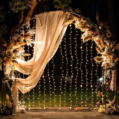 Elegant wedding backdrop with lights and floral arrangements.