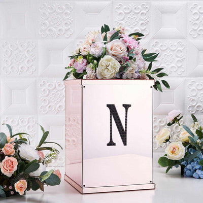 Floral arrangement in a mirrored box with an "N" monogram on a textured background.