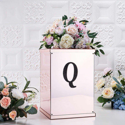 Elegant floral arrangement in a mirrored box with a large "Q" on the front.