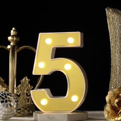 Yellow illuminated number 5 decorative light with a marble base.