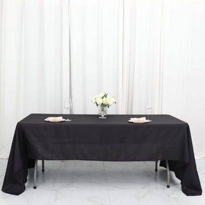 Elegant black tablecloth draped over a table set with flowers and dinnerware.
