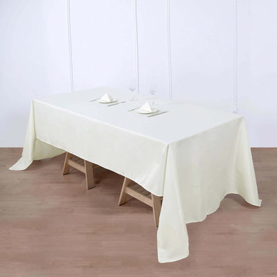 Elegant cream tablecloth on a wooden table with dinnerware setup.