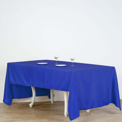 Blue tablecloth draped over a dining table with plates and glasses.