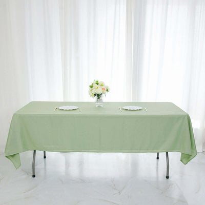 Green tablecloth on a dining table with floral centerpiece and plates.
