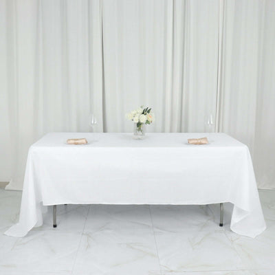 Elegant white table setup with flowers and glassware for a sophisticated dining experience.