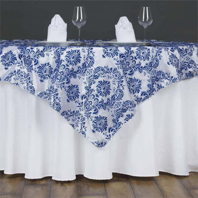 Blue and white floral tablecloth on a white table with glasses and napkins.