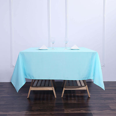 Light blue tablecloth draped over a wooden table with glasses and napkins.