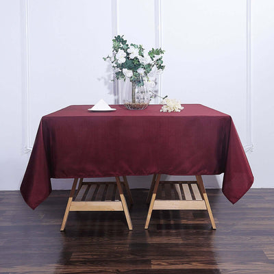 Burgundy tablecloth draped over a wooden table with floral arrangement