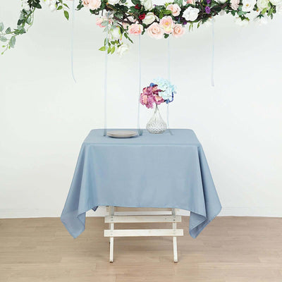 Blue tablecloth draped over a wooden table with floral decor and a vase.