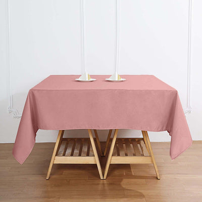 Pink tablecloth draped over a wooden table with candle holders.