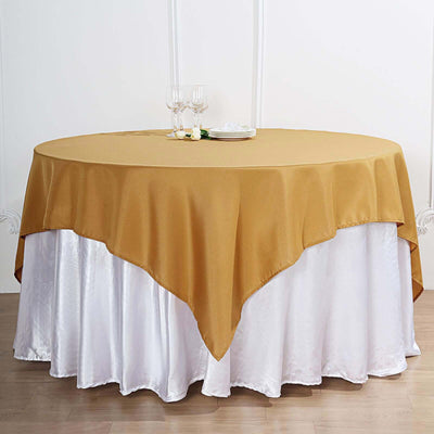 Gold tablecloth draped over a white table skirt in a studio setting.