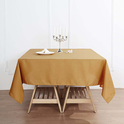 Mustard tablecloth draped over a wooden table with a candle holder and plate.