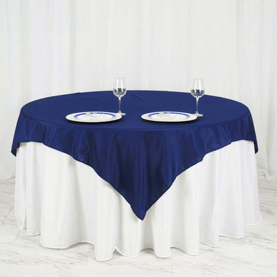 Round navy tablecloth draped over a white table with plates and glasses.