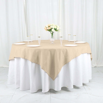 Beige tablecloth draped over a round table with decorative flower arrangement.