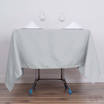 Gray tablecloth on a folding table with glasses and napkins set for dining.