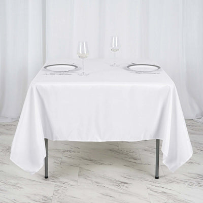White tablecloth set with plates and glasses on a dining table