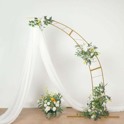 Gold wedding arch with white drapery and floral arrangements