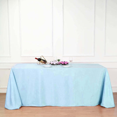 Light blue tablecloth draped over a table with wine and flowers