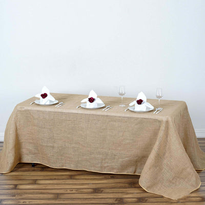 Elegant burlap tablecloth draped over a dining table with set tableware.