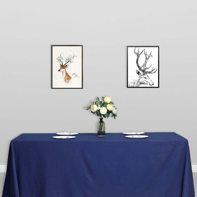 Framed deer art prints above a table with a blue tablecloth and flowers.