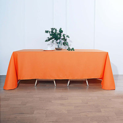 Orange tablecloth draped over a table with a plant centerpiece.