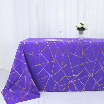 Purple tablecloth with gold geometric pattern on a table.