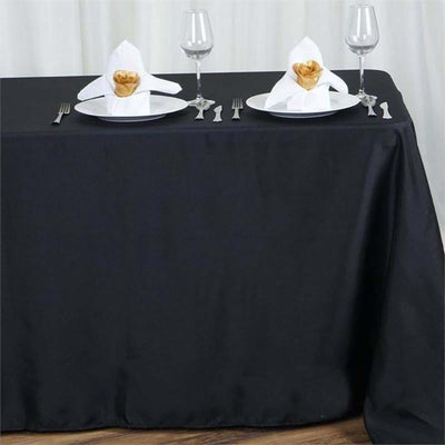 Elegant black table setting with napkin art and wine glasses.