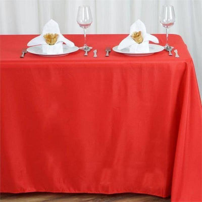 Red tablecloth with elegant table setting and napkin folds.