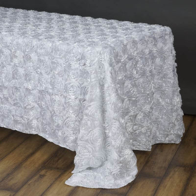 White rose-patterned tablecloth draped over a wooden table.
