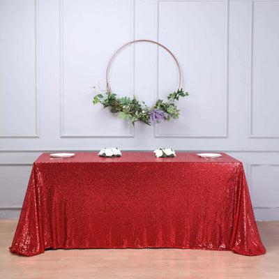 Red sequin tablecloth draped over a table, styled with floral decor.