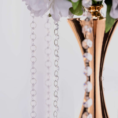 Elegant golden vase with clear crystal chains and floral arrangement.