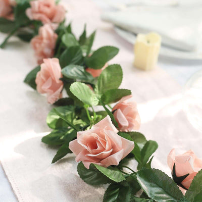 Peach artificial roses on a table runner for elegant decor.