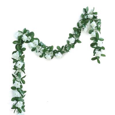 Artificial white flower garland with green leaves on a plain white background